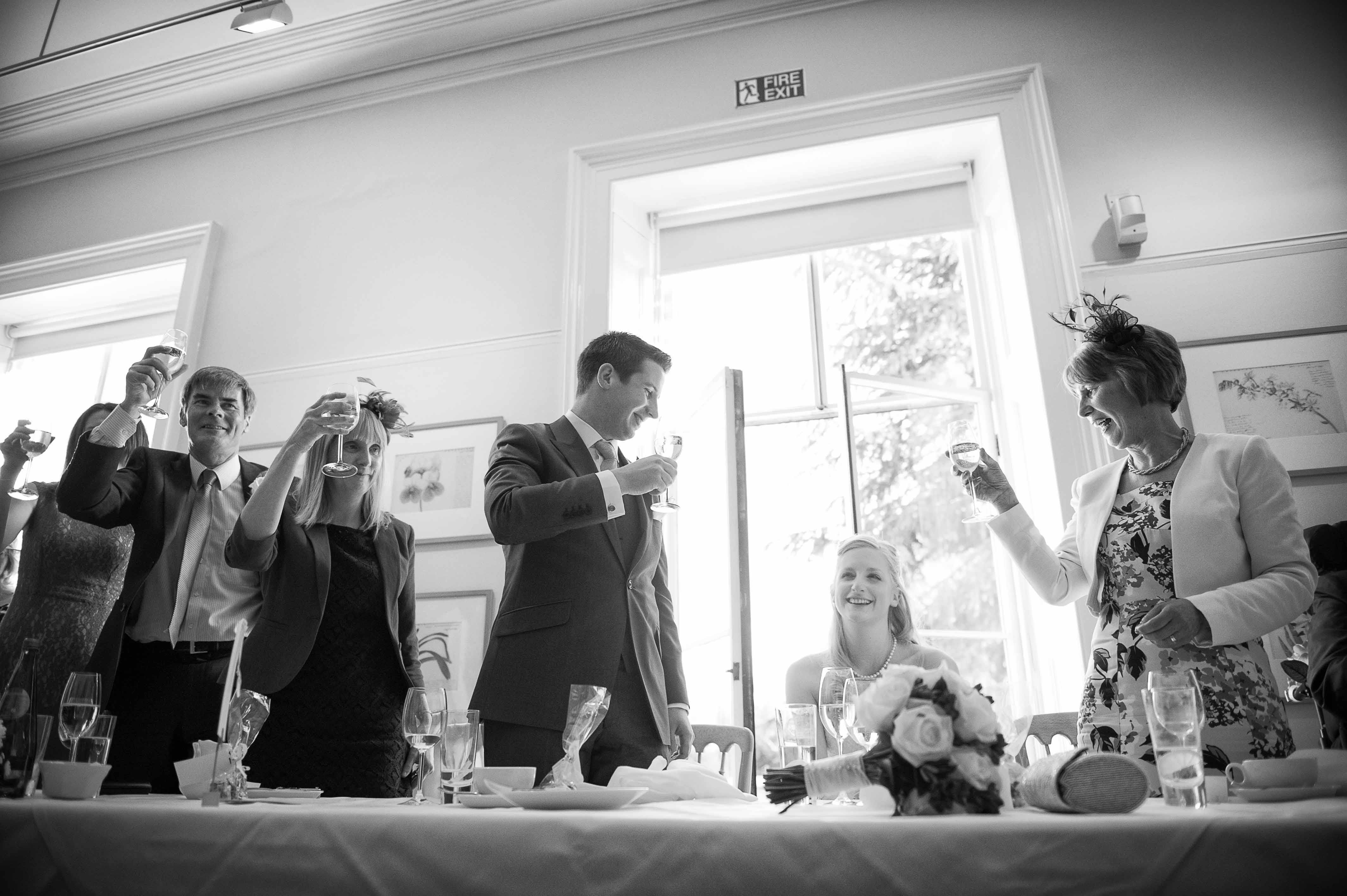 Groom and guests toasting the bride at their wedding dinner