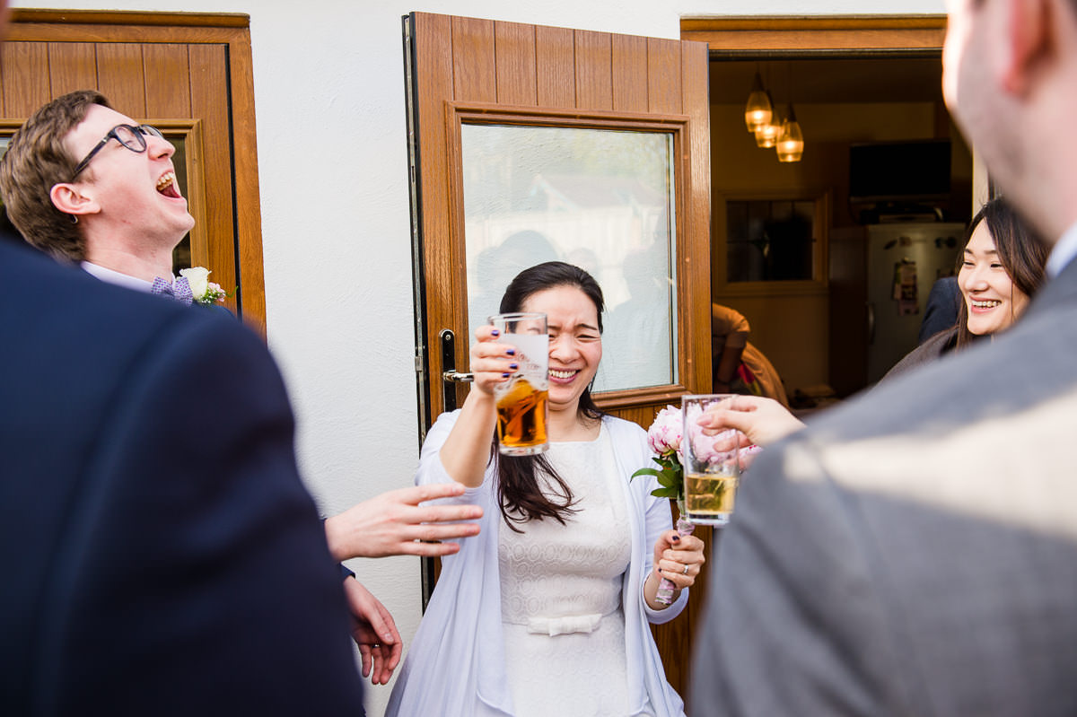 Bride and Groom clinking pints at their surrey garden wedding