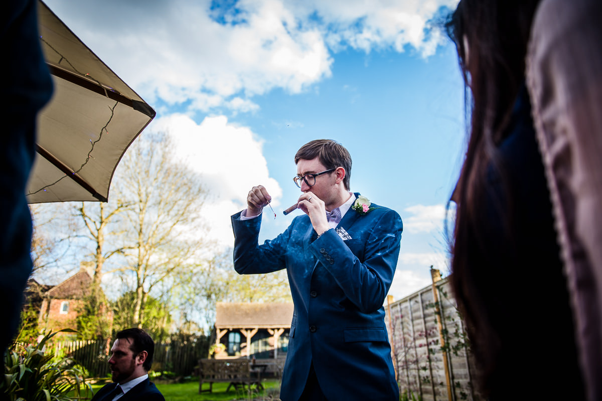 Groom smoking a cigar at his relaxed surrey garden wedding