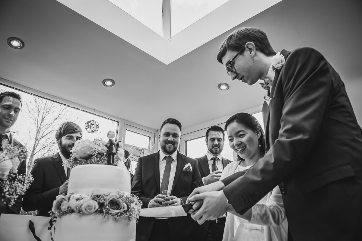 Bride and Groom curling their wedding cake at their surrey garden wedding