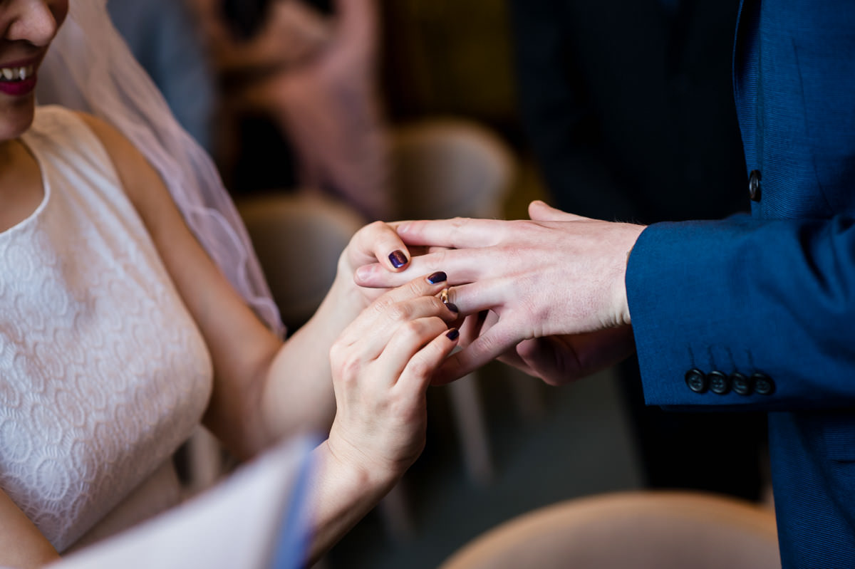 Bride placing wedding ring on Groom's finger during their wedding