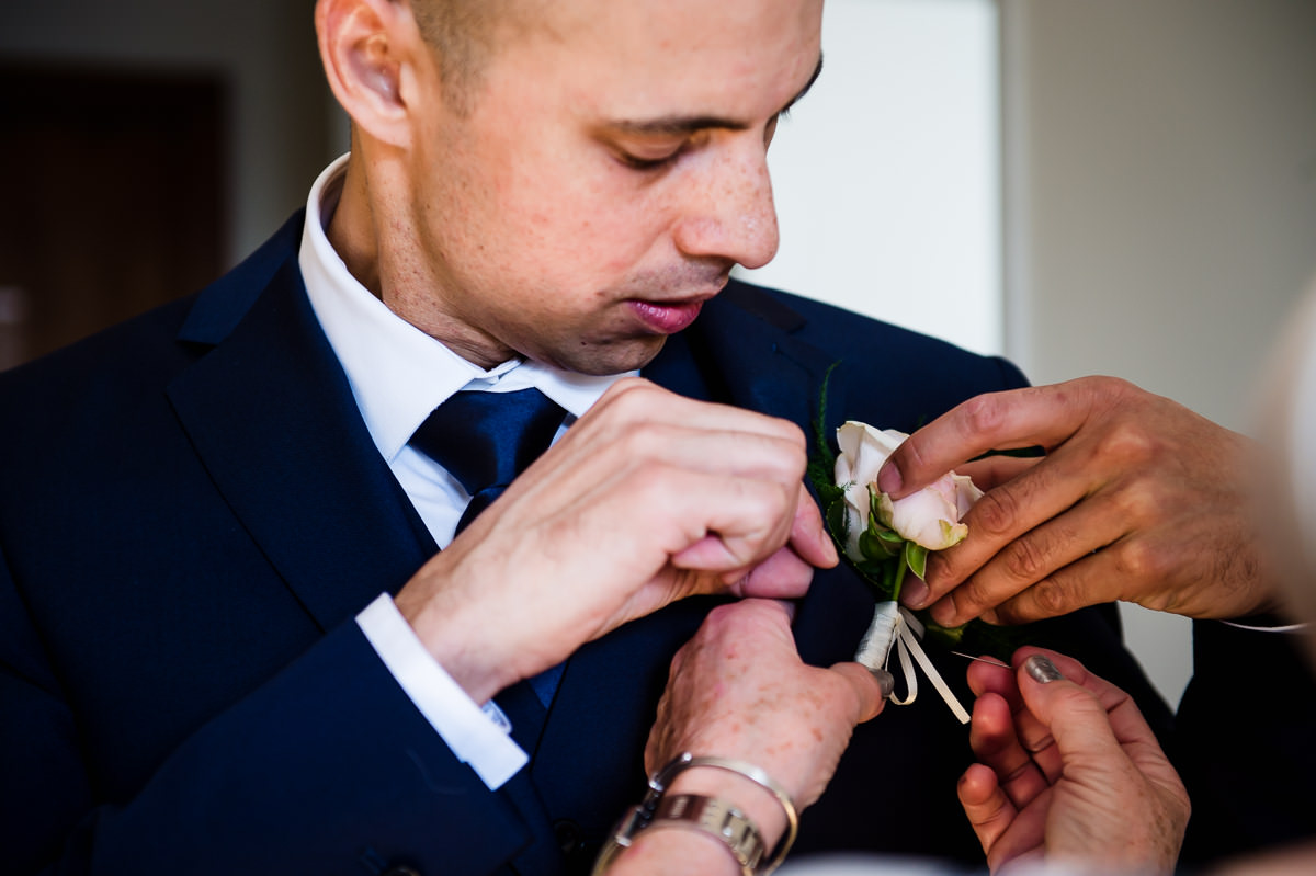 Bethnal Green Town Hall Hotel wedding groom putting on button hole