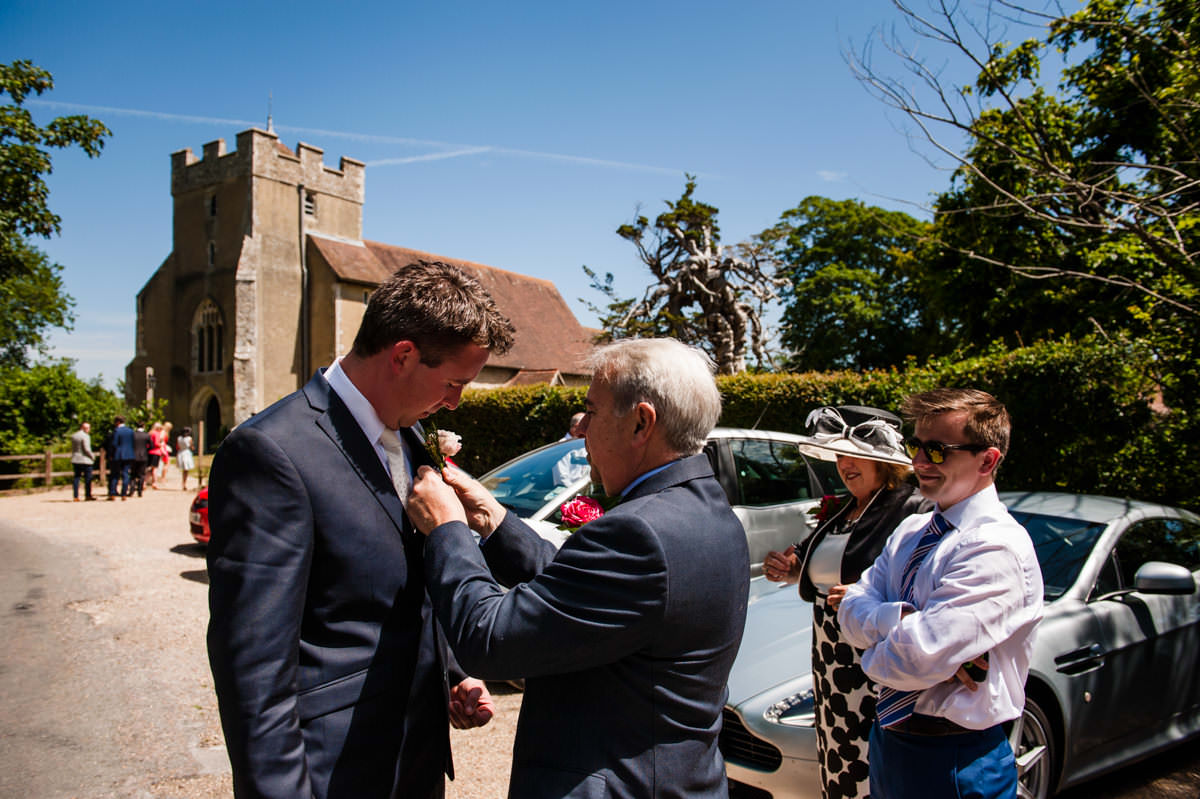 groom's dad helps him put on his wedding buttonhole
