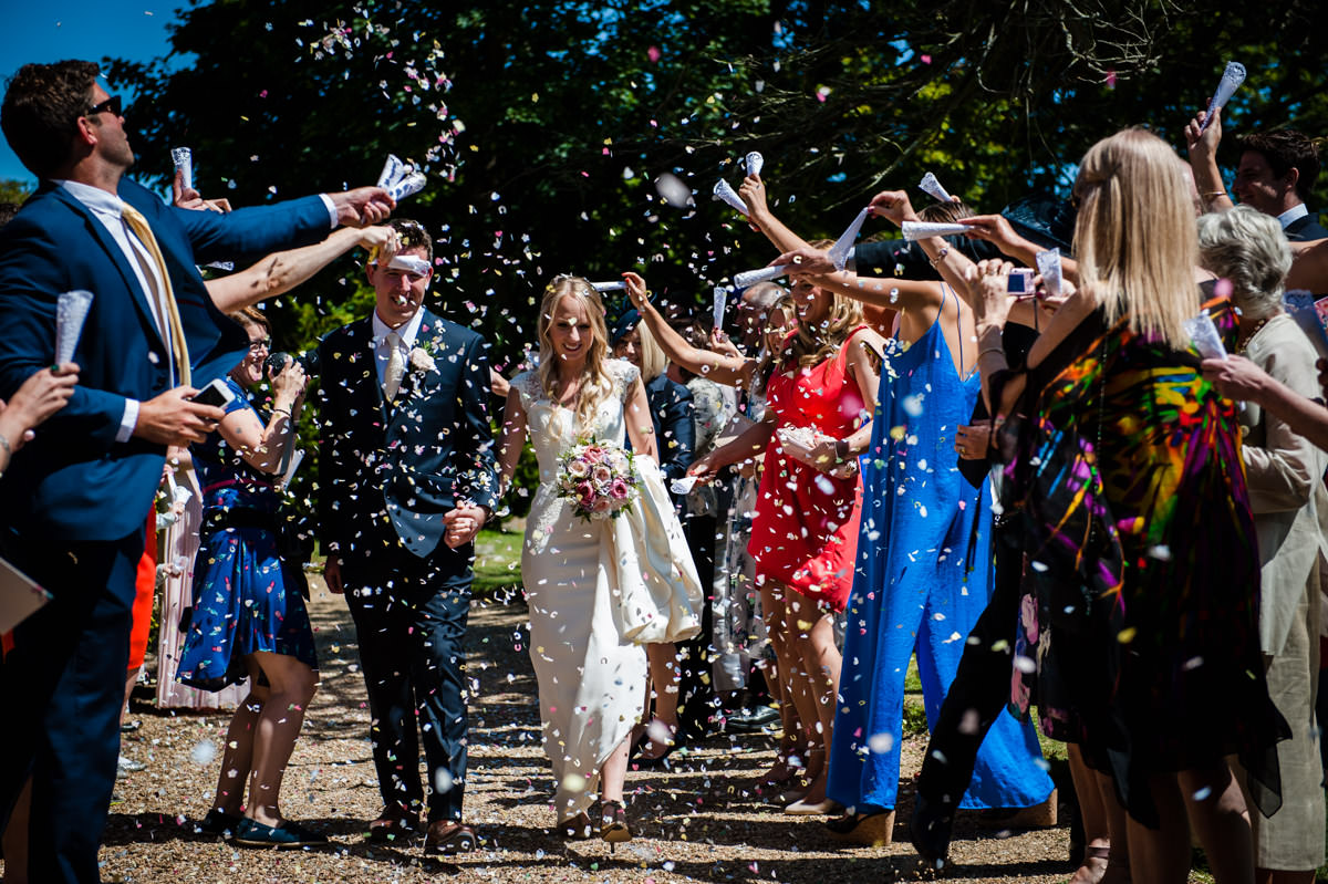 Bride and Groom walking through confetti shower after their west sussex wedding