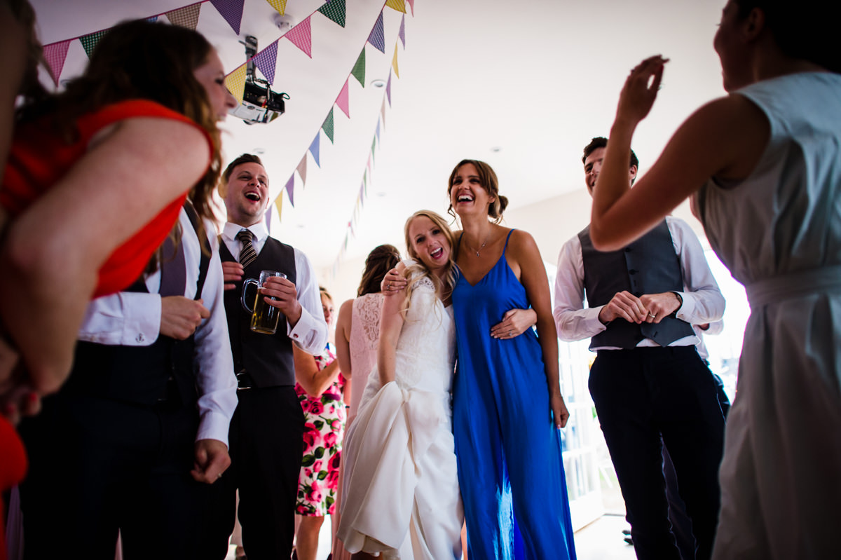 Bride surrounded by friends dancing at her Sussex wedding