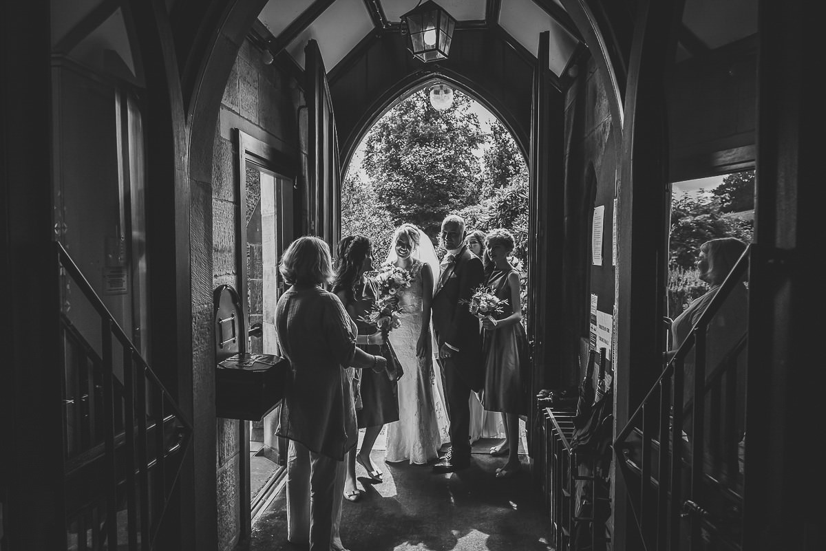 Bride waiting at the church door with her dad and bridesmaids, ready for the wedding