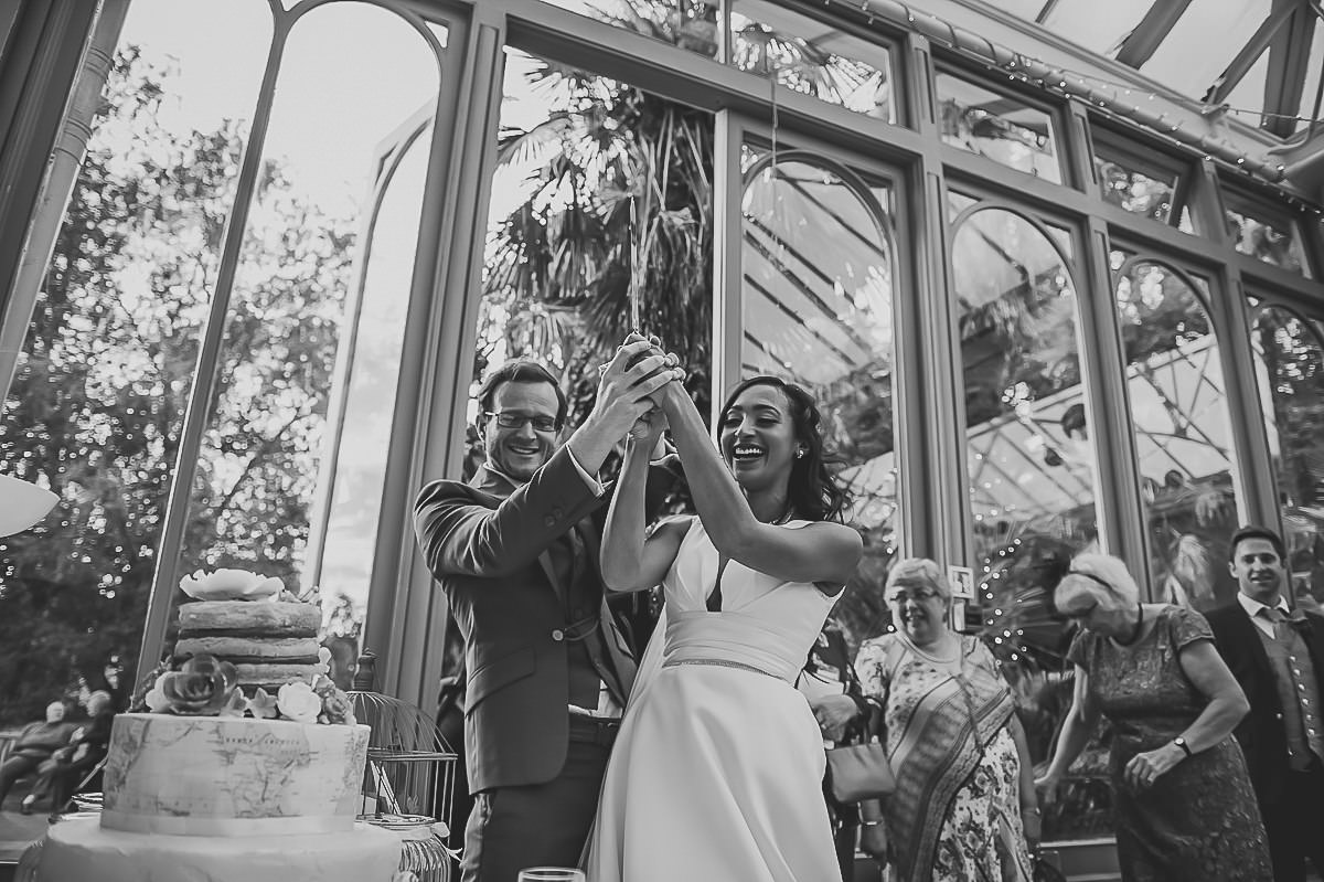 Bride and Groom attacking their wedding cake at their Hampton Court House wedding
