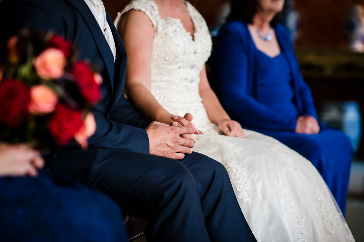 Close up photo of bride and groom holding hands