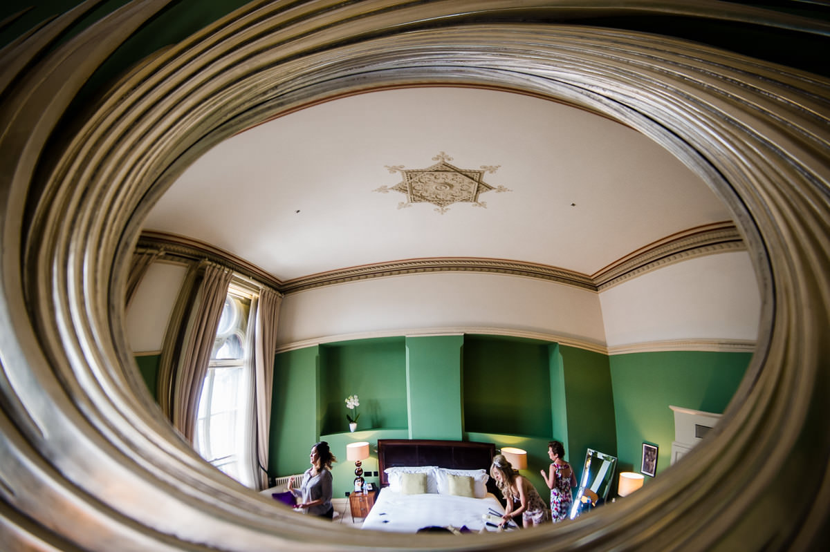 Reflection in bedroom mirror of bride and bridesmaids getting ready at St Pancras Renaissance Hotel, London