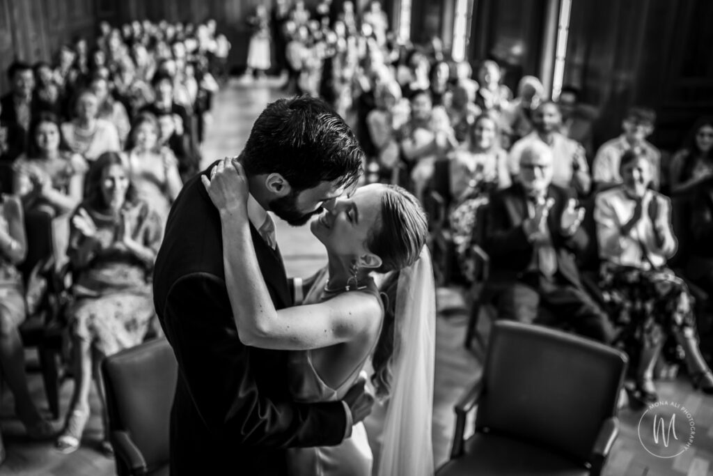 bride and groom kissing in front of their guests at hackney town hall