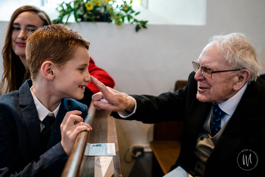 Grandad touching grandson's nose at his granddaughter's wedding