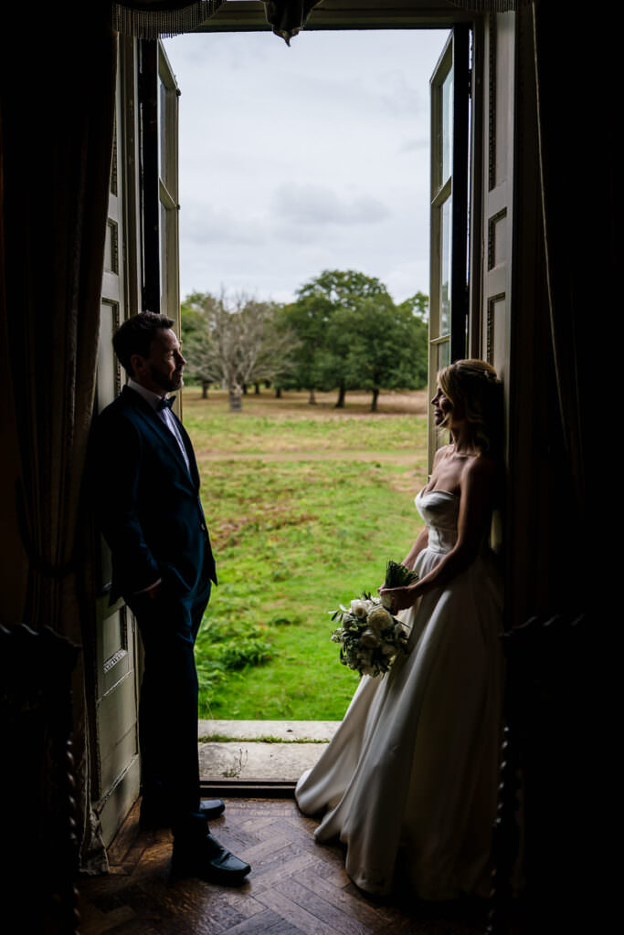Bride and groom leaning against the doors into bushes park at their Hampton court house wedding